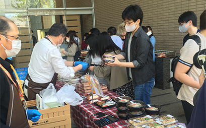 特設の販売所に並んだ地元飲食店の弁当を選ぶ学生
