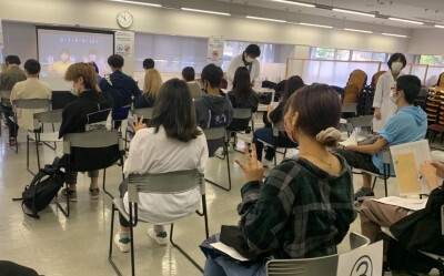 千葉東金キャンパスの接種会場で、動画を見ながら指の運動をする学生