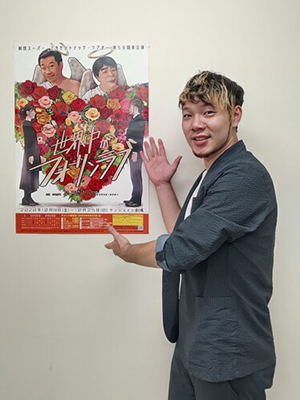 自身のイラストが描かれた公演ポスターを紹介する富山さん